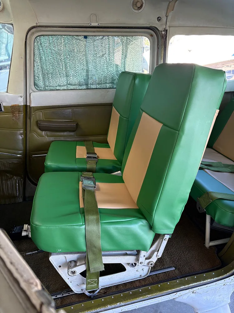 The rear passenger seats of a small aircraft, upholstered in green and tan vinyl.