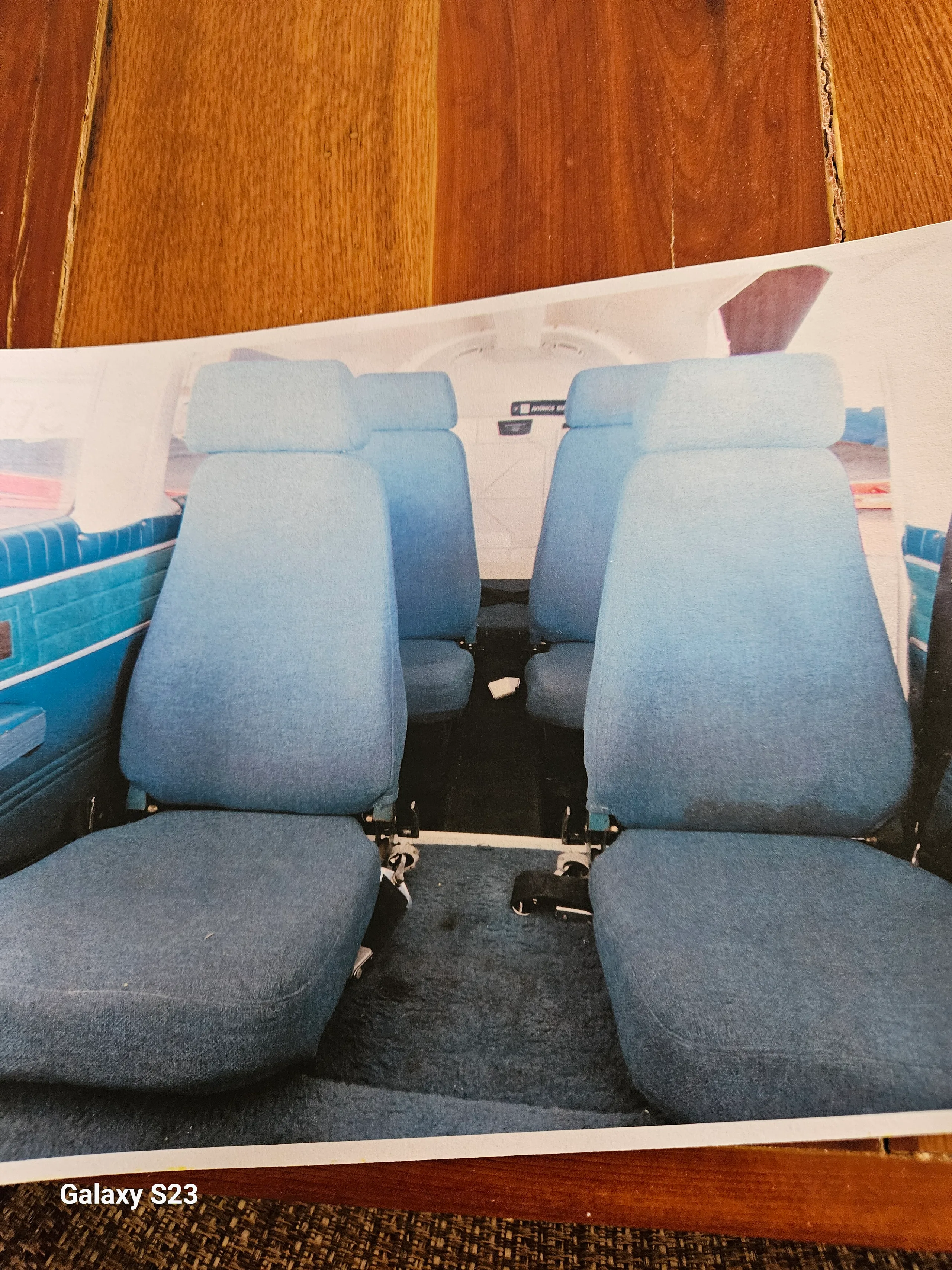 The interior cabin of an aircraft, featuring blue fabric seats arranged in rows.