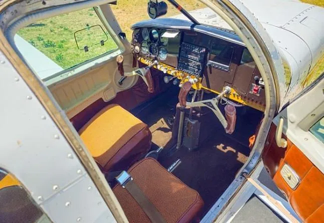 An overhead view into the cockpit of an aircraft, showing the instrument panel and brown front seats.