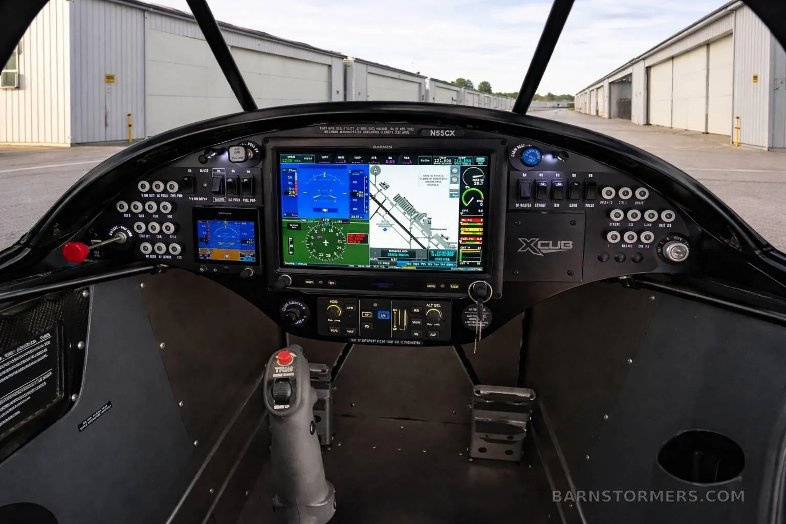 The cockpit of an X-Cub aircraft, featuring a modern glass panel display with navigation information and a joystick control.