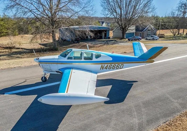 A side view of the white and blue single-engine aircraft N4666D parked on an asphalt runway.