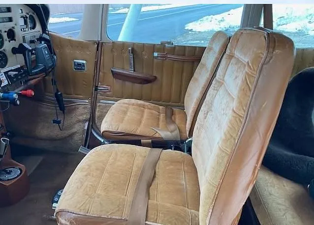 The interior cabin of the aircraft, showing two tan upholstered seats and the side panel.