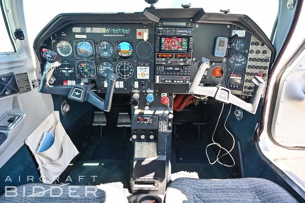 The cockpit of a small aircraft features a detailed instrument panel with analog gauges and modern avionics.