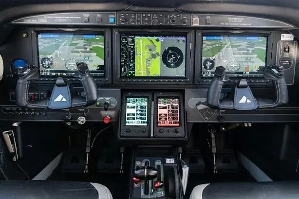 The cockpit of a Piper M600, featuring a modern glass panel with three large display screens and dual yokes.