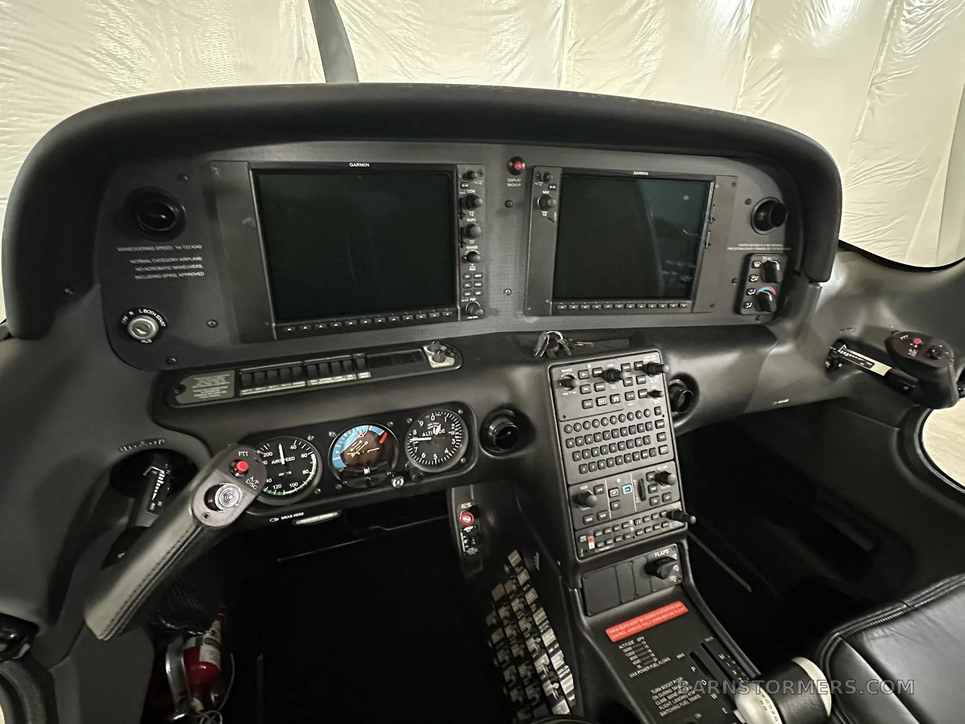 The cockpit of a small aircraft, featuring two large Garmin displays and a complex array of buttons and gauges.
