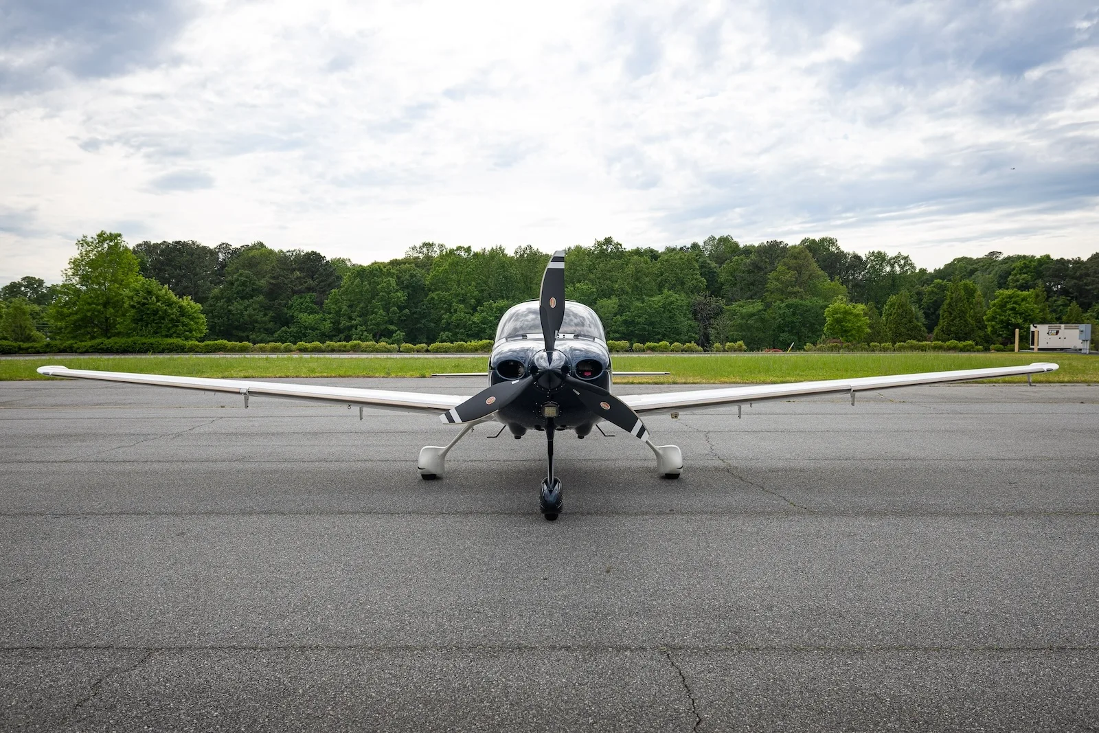 A white and dark blue Cirrus SR22T aircraft with registration N564N viewed from the front on an asphalt ramp.