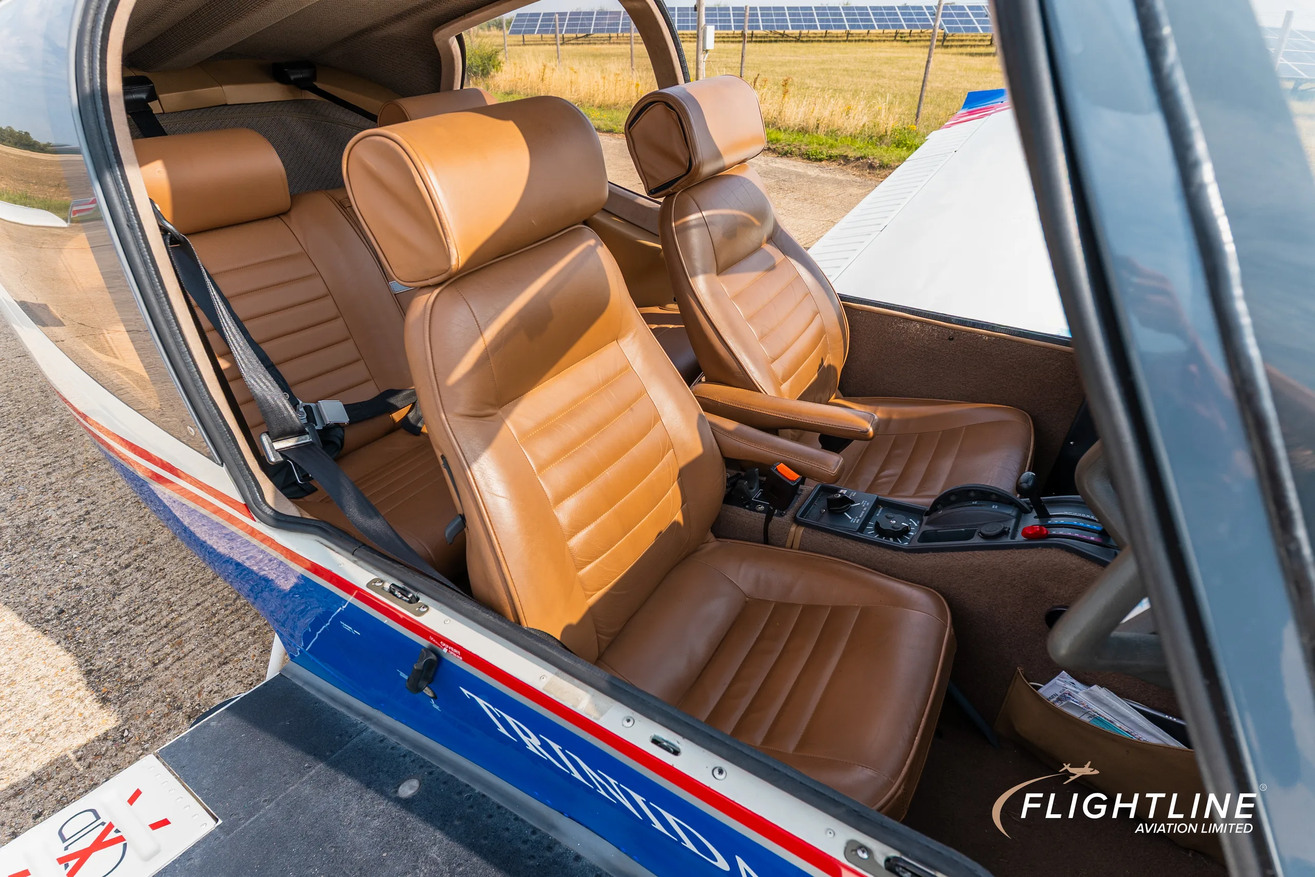 A view into the N377C Socata Trinidad GT's cabin, showing the tan leather front and rear seats from the right side.