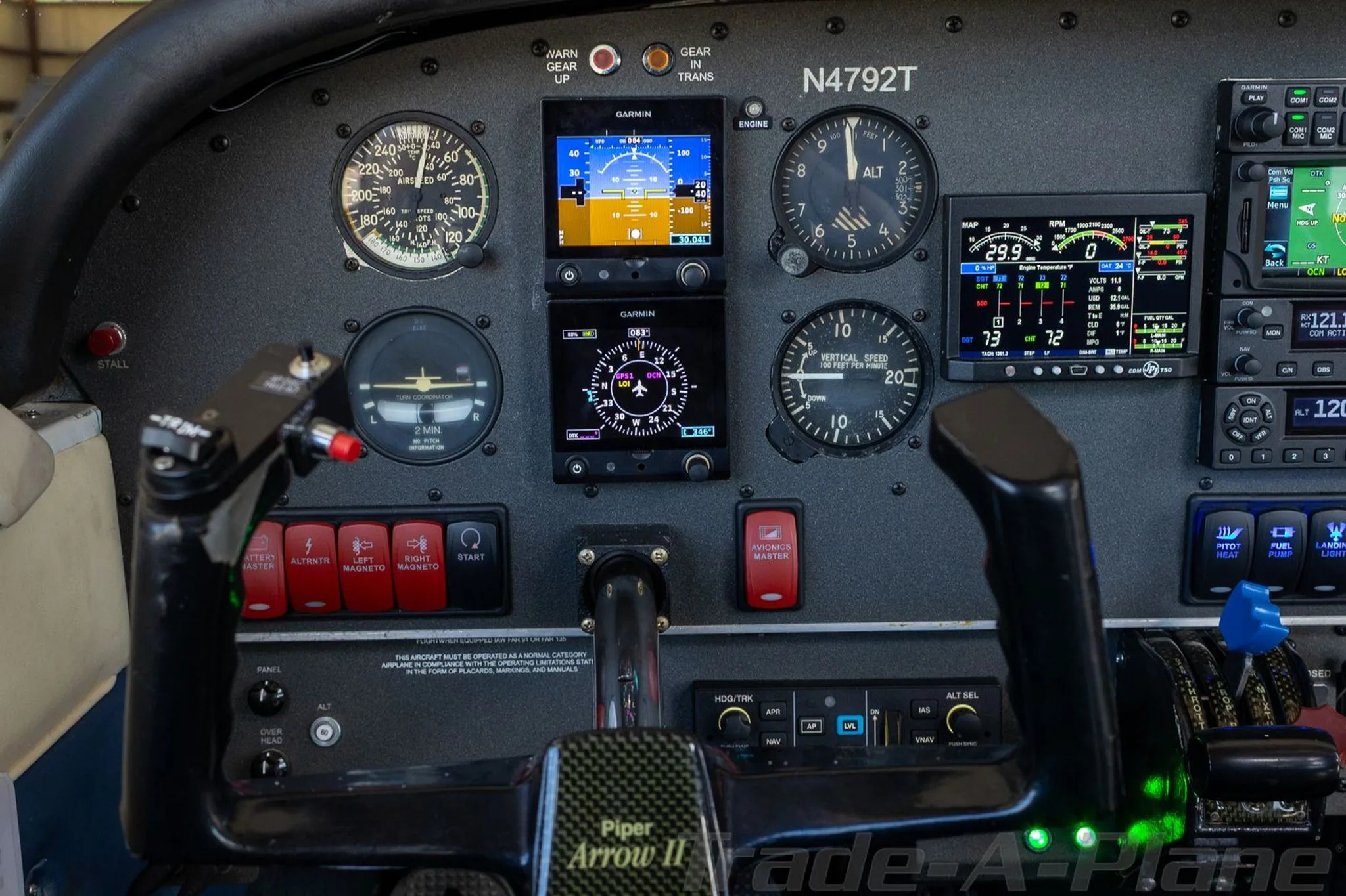Close-up view of the Piper Arrow II cockpit instrument panel, featuring analog gauges and modern Garmin displays.