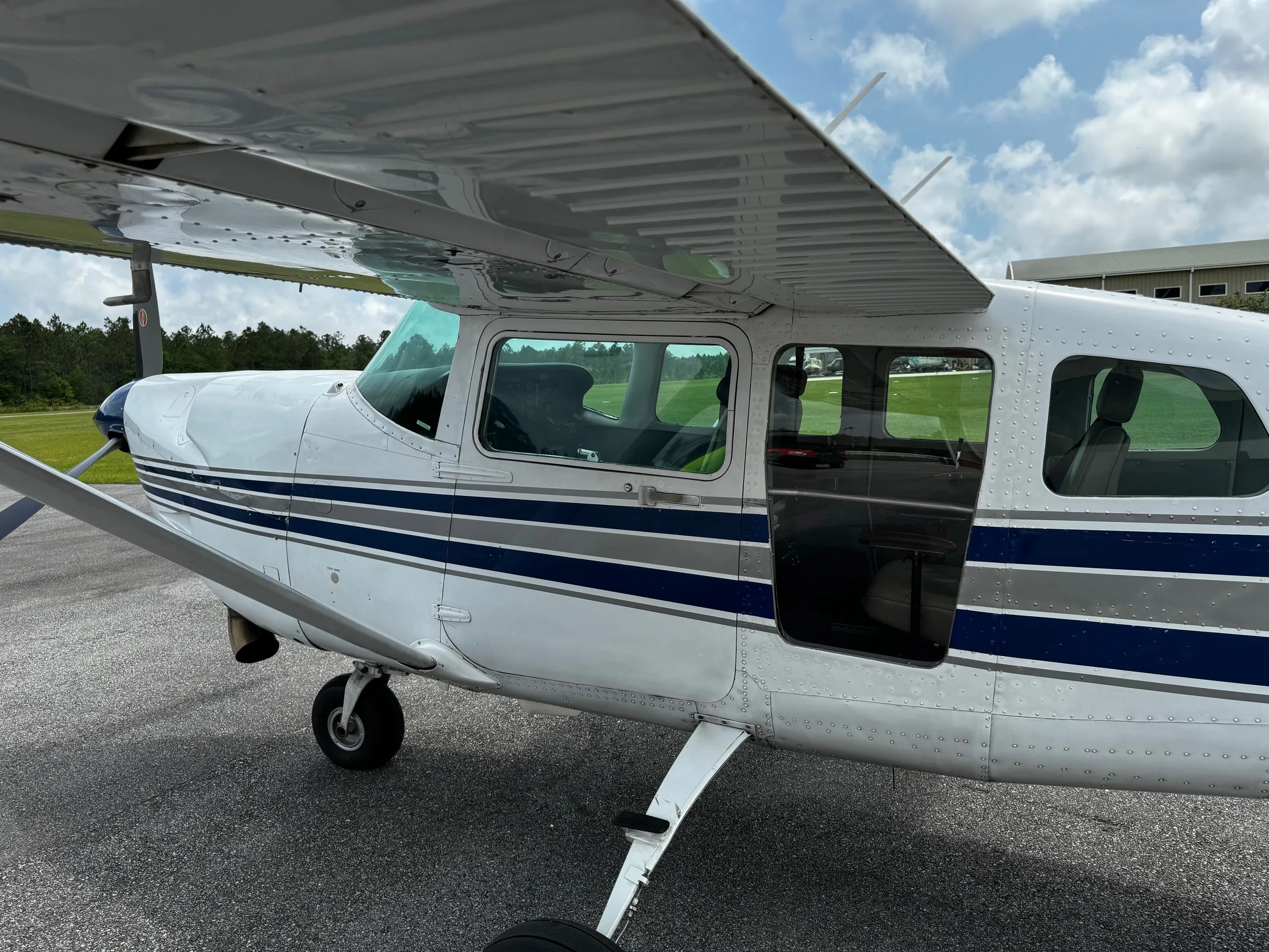 Close up of the side of a white and blue Cessna 206 Turbo Stationair with the door open.