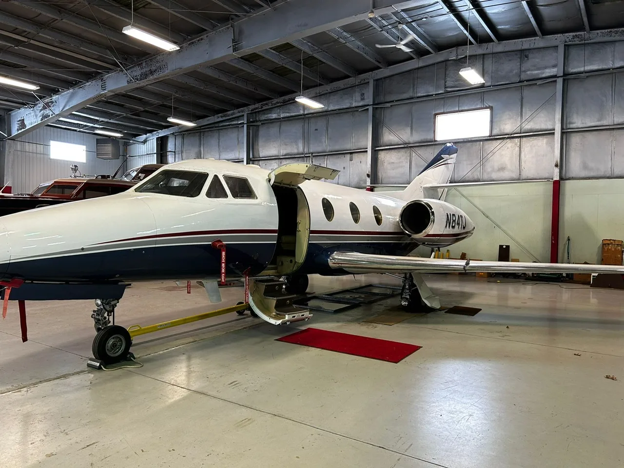 Close up side view of the aircraft N84TJ in a hangar with the door open.
