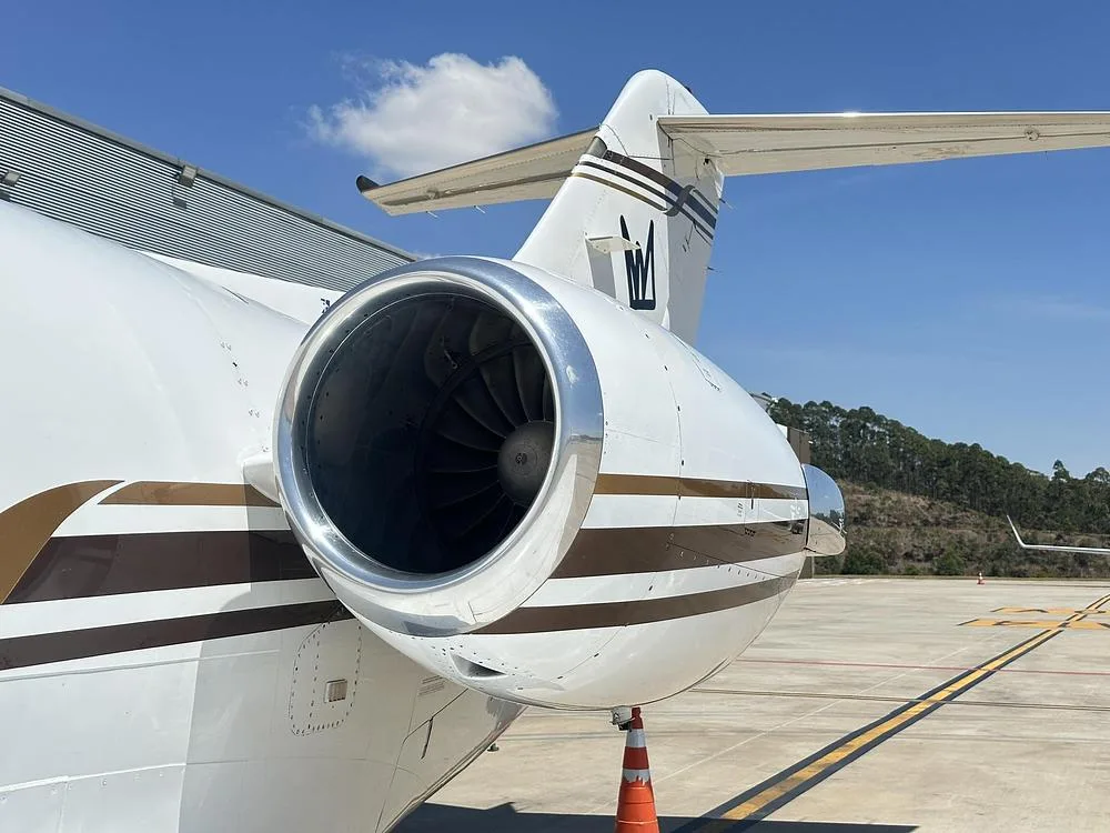 A close-up view of the right engine and tail of a white business jet with brown stripes.