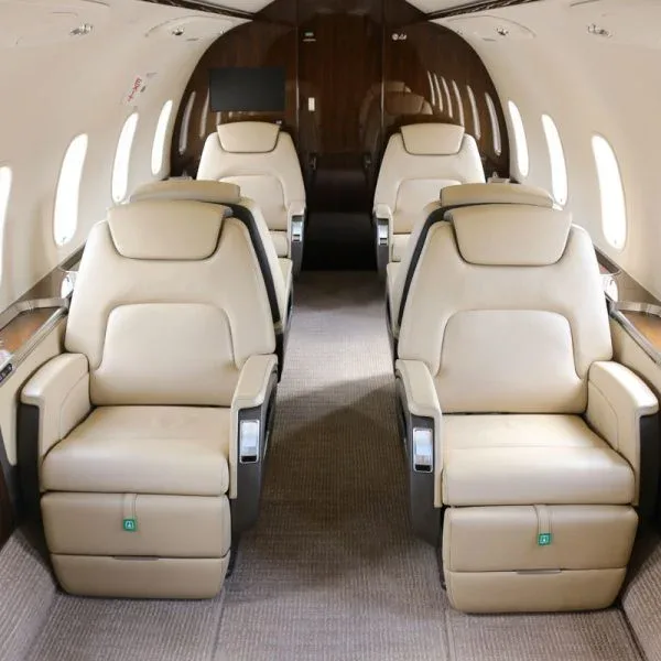 View of a luxurious aircraft cabin with four beige leather seats arranged in a club configuration.