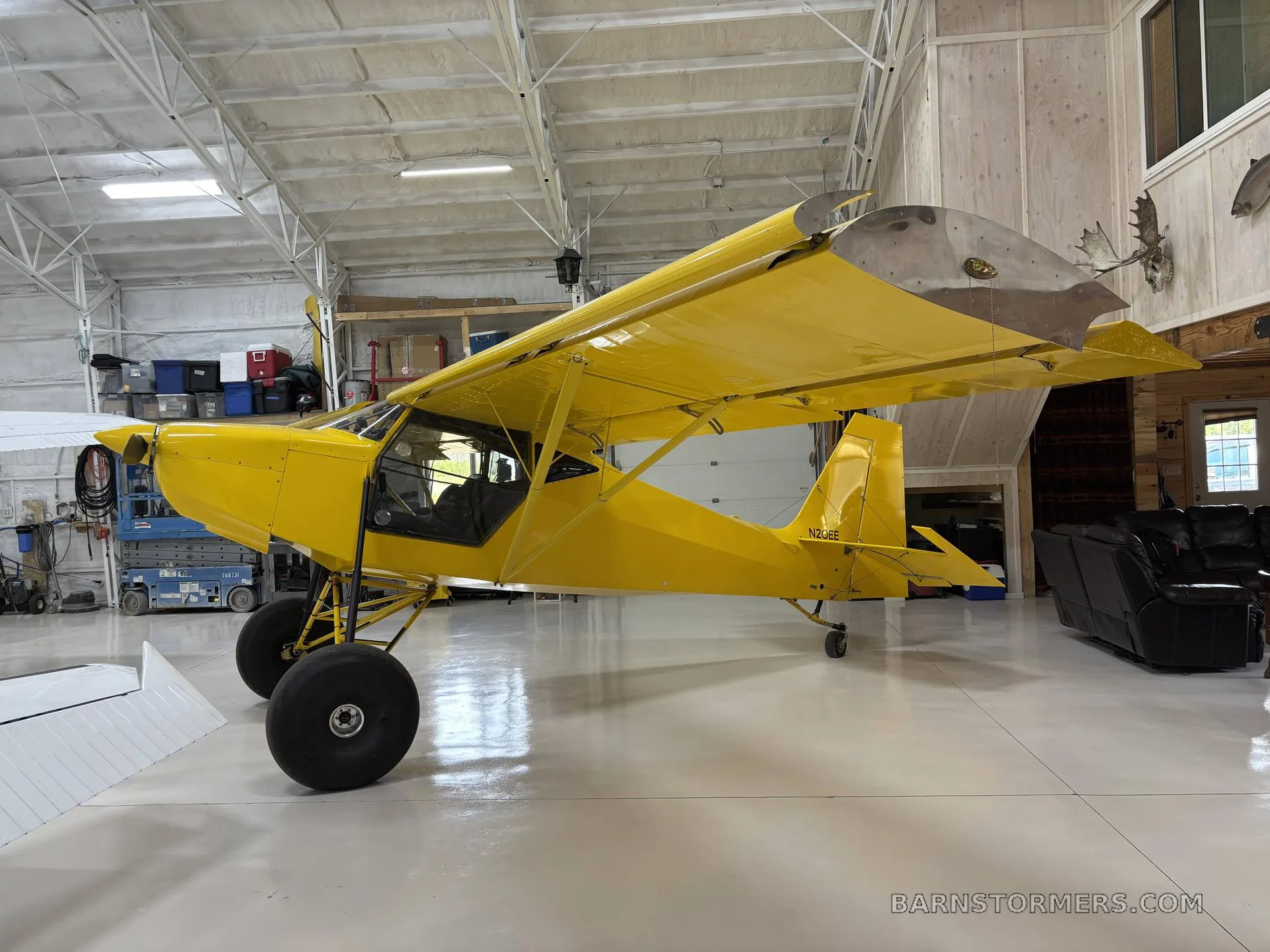 A bright yellow single-engine bush plane with large tires, parked inside a hangar.