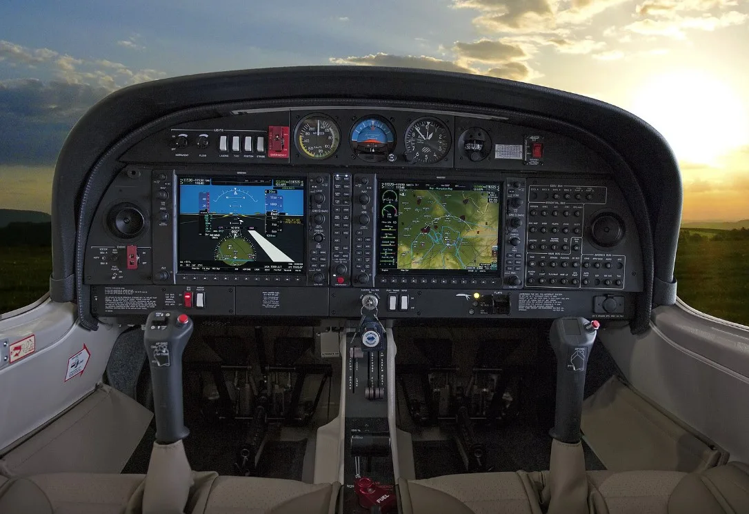 The cockpit of a Diamond aircraft with a modern glass panel display and a sunset sky visible through the windshield.