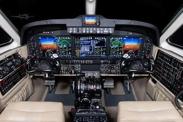 The aircraft cockpit features a modern glass panel display with multiple screens, yokes, and a central throttle quadrant.