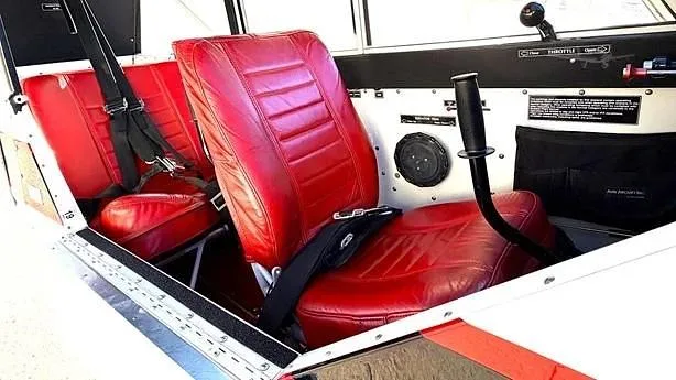 The aircraft's interior features two red upholstered seats with visible seatbelts.