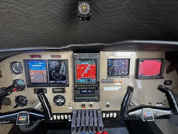 The cockpit of an aircraft featuring multiple modern glass displays, traditional gauges, and control yokes.