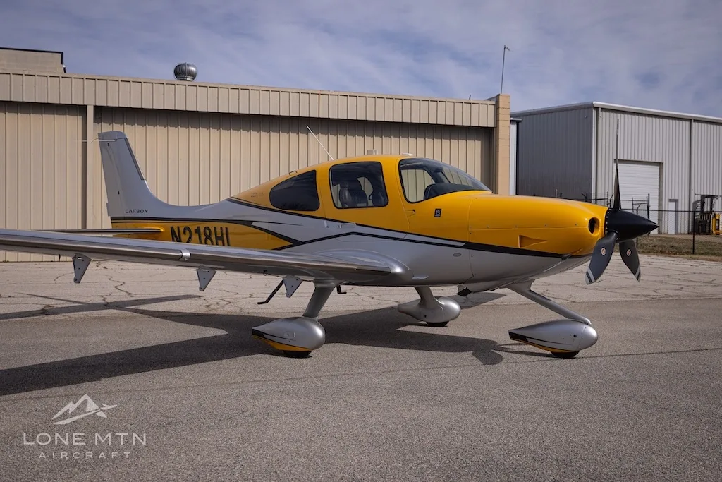 A Cirrus SR22 aircraft with yellow and silver paint scheme parked on an airfield.