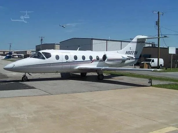 A white business jet, likely a Citation, with registration N922TR, parked on a tarmac with hangars in the background.