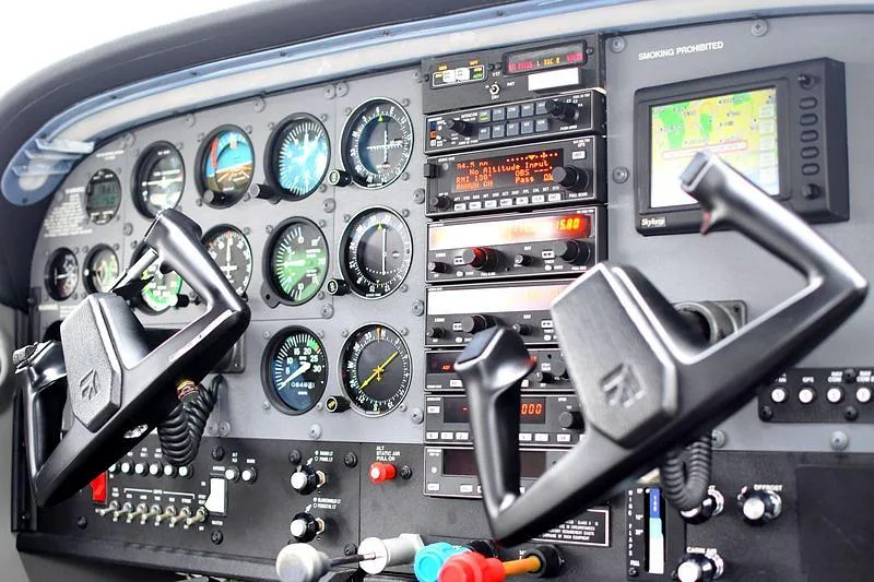 The cockpit instrument panel of a small aircraft, featuring analog gauges, avionics, and two control yokes.