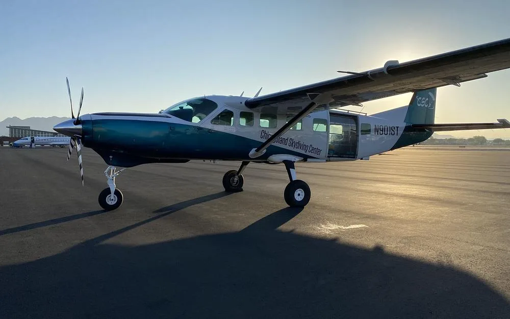 A teal and white single-engine turboprop aircraft, N901ST, is parked on an airfield at sunset.