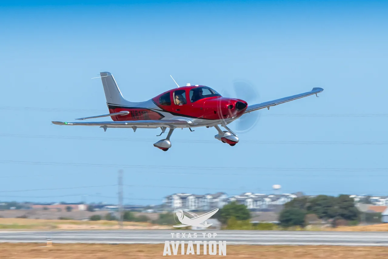 A red and silver Cirrus SR22T GTS aircraft taking off from a runway.