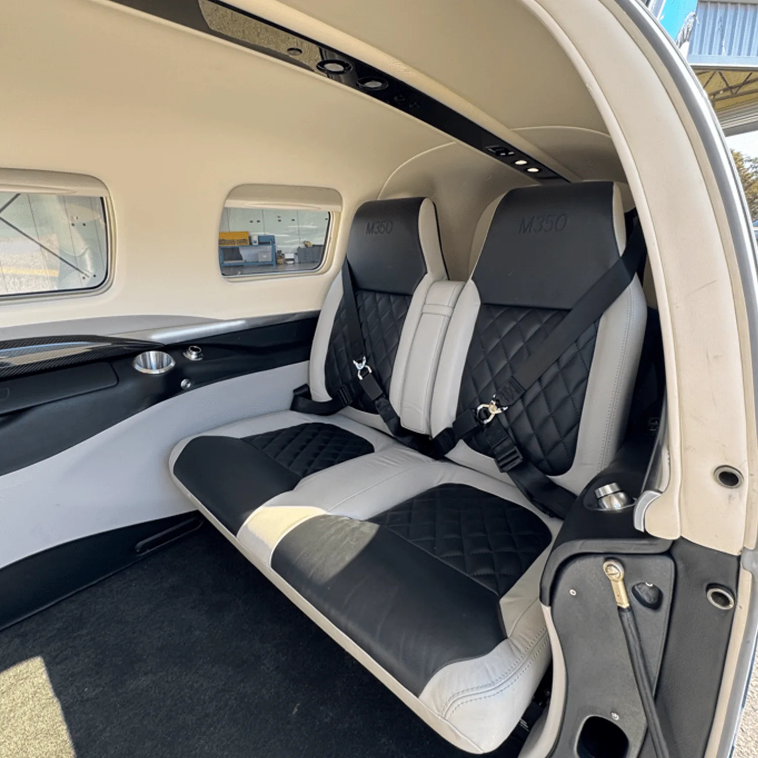 The rear cabin interior of a Piper M350 aircraft with black and white quilted leather seats.
