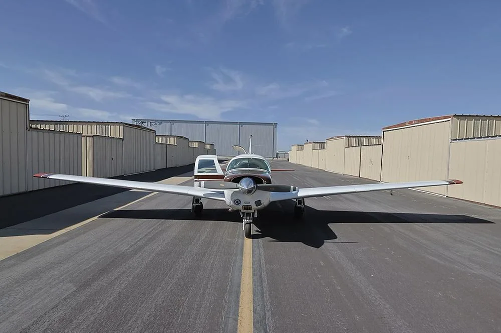 A head-on view of the brown and white single-engine aircraft, N6829V, centered on an asphalt taxiway.