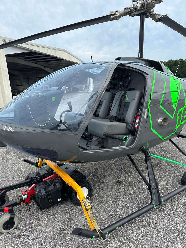 A close-up view of the open cabin and gray seats of the N88ZH Enstrom helicopter.