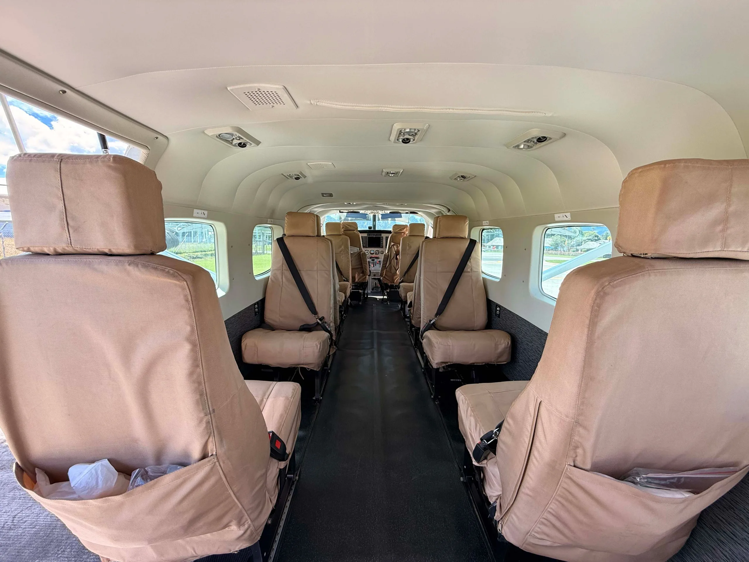 The interior cabin of an aircraft with rows of tan fabric seats.