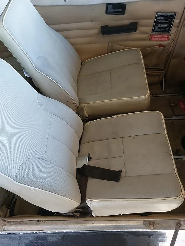 Two rows of light-colored aircraft seats with seatbelts are visible in the cabin interior.