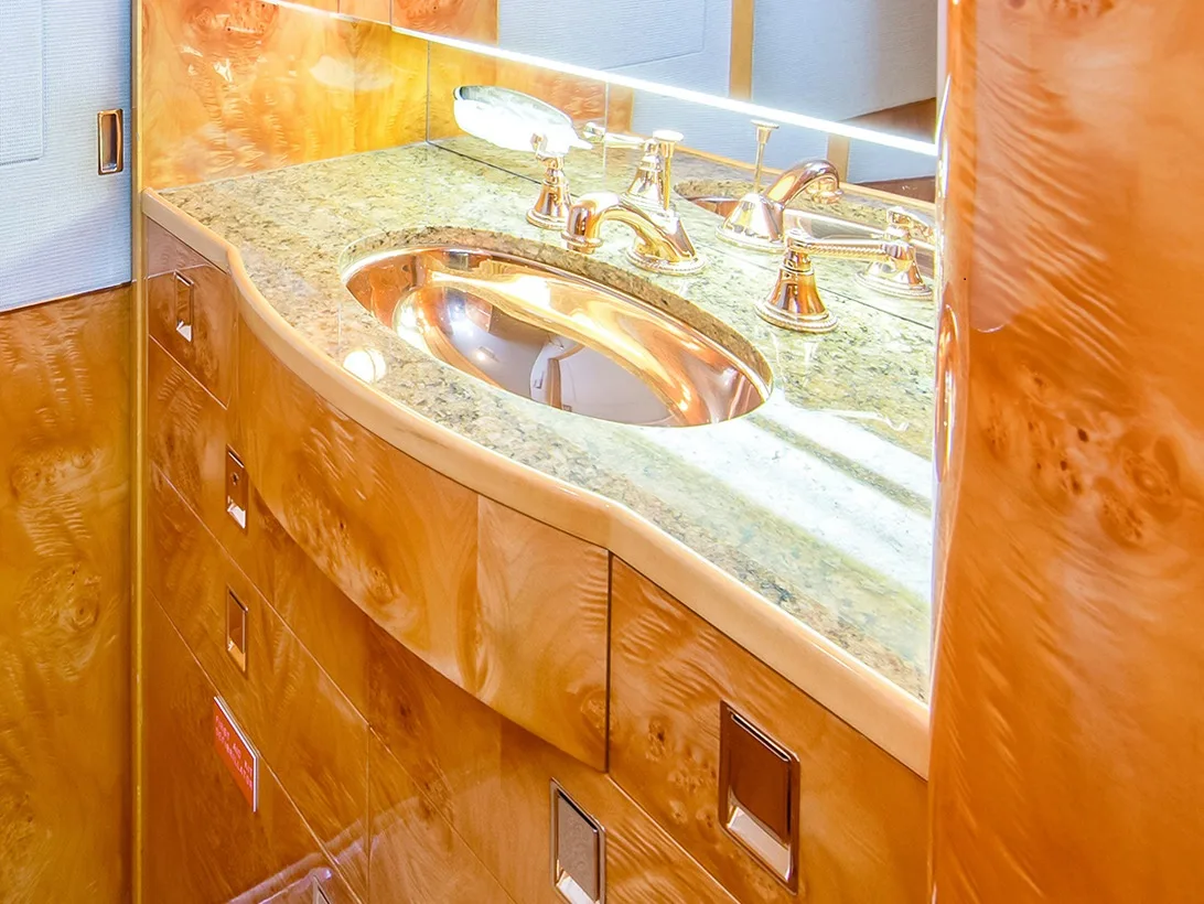 Aircraft lavatory with gold fixtures and wood trim.