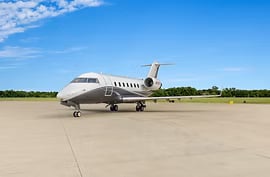A gray and white jet parked on the tarmac under a blue sky.