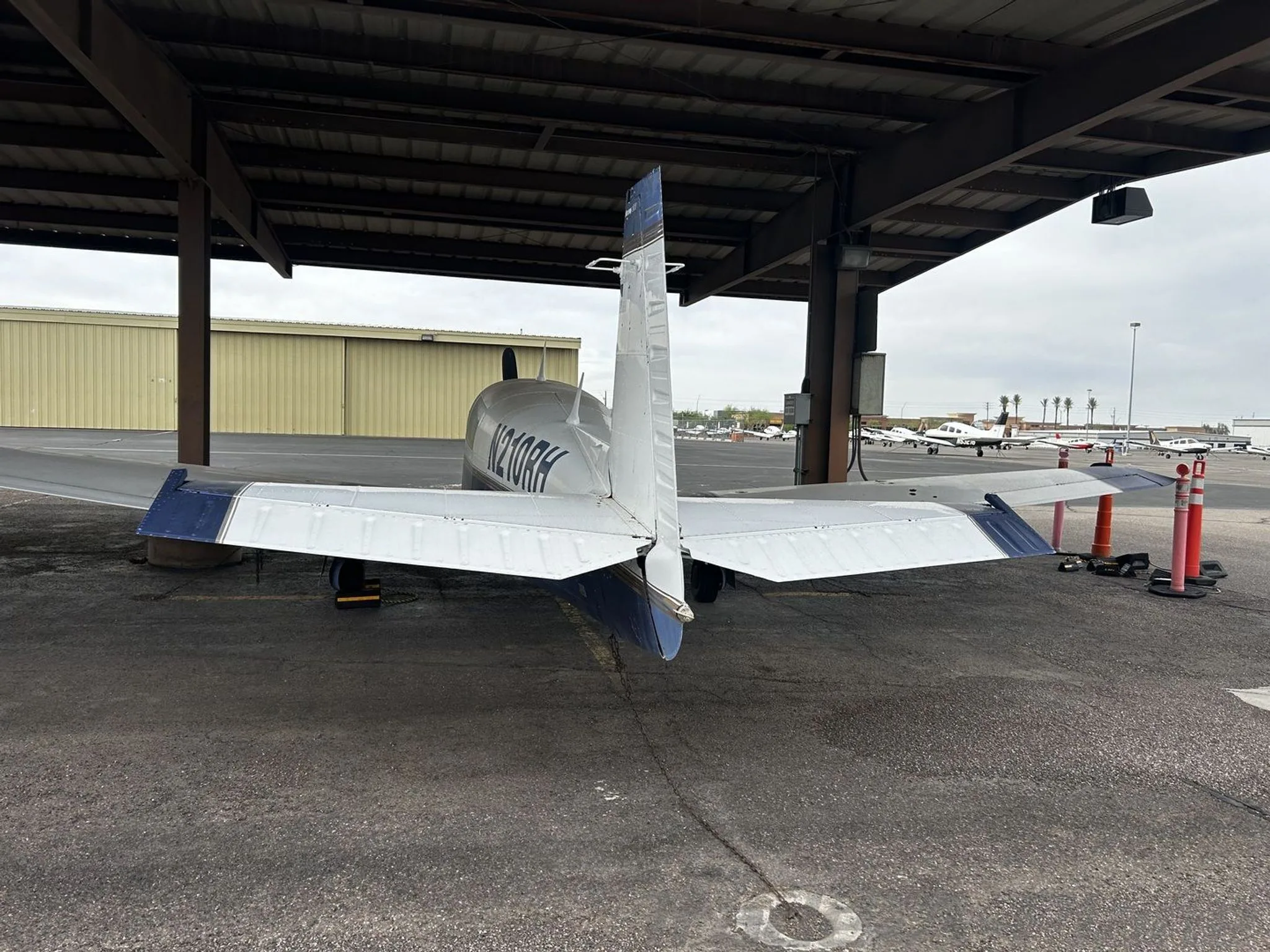 Rear view of the blue and white single-engine aircraft N210RH showing its tail and horizontal stabilizer.