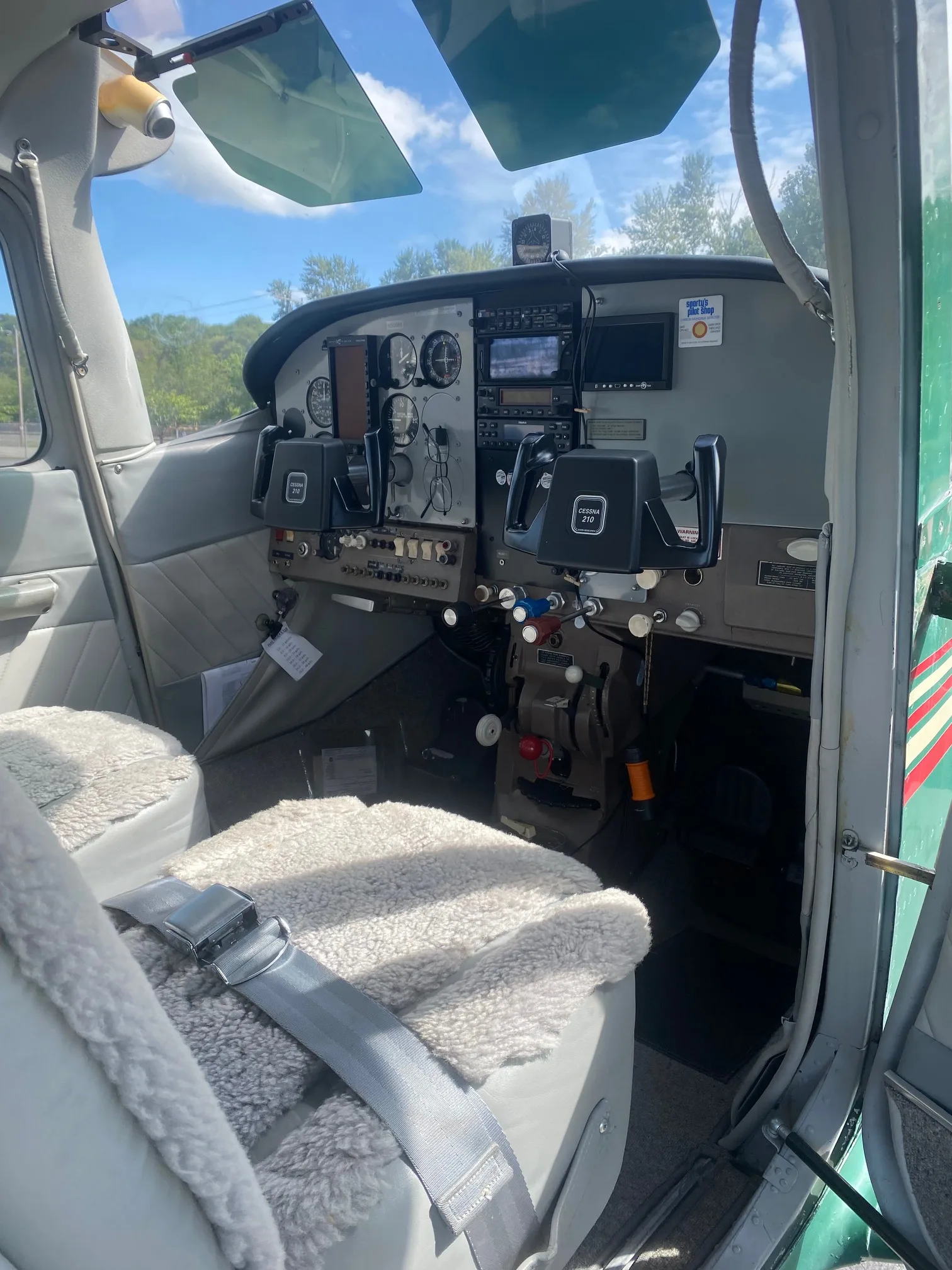 Interior view of the Cessna 210 cockpit with instrument panel and sheepskin-covered front seats.