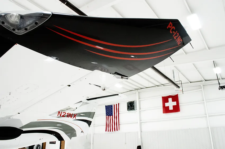 A head-on view of a white Pilatus PC-12NG turboprop aircraft with its four-bladed propeller in a hangar.