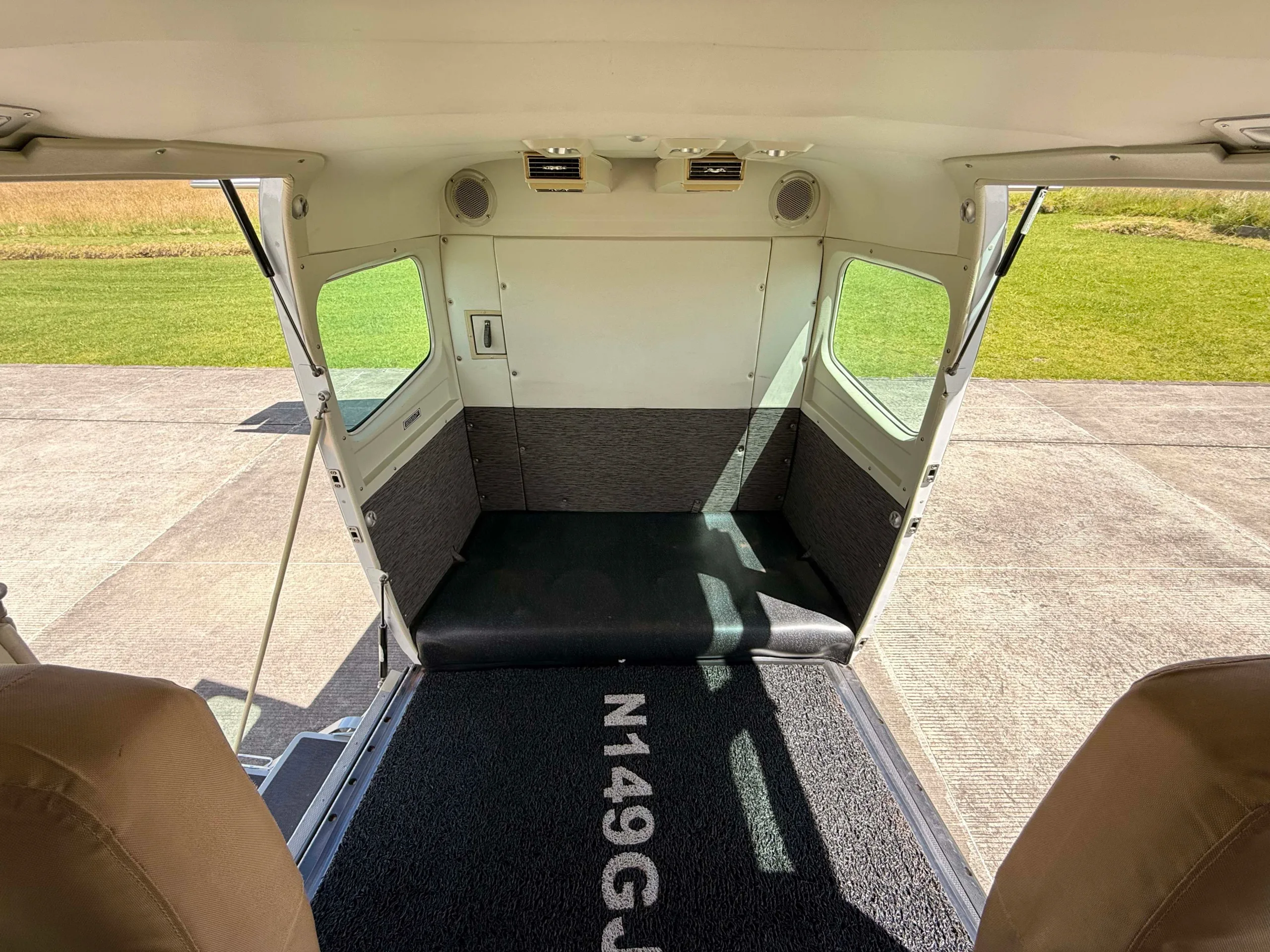 The rear cargo area of an aircraft with "N149GJ" on the floor mat, looking out the open door.
