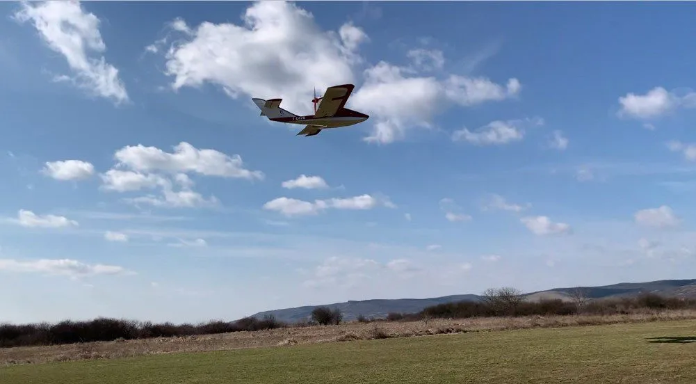 Osprey 2 aircraft in flight over a field.