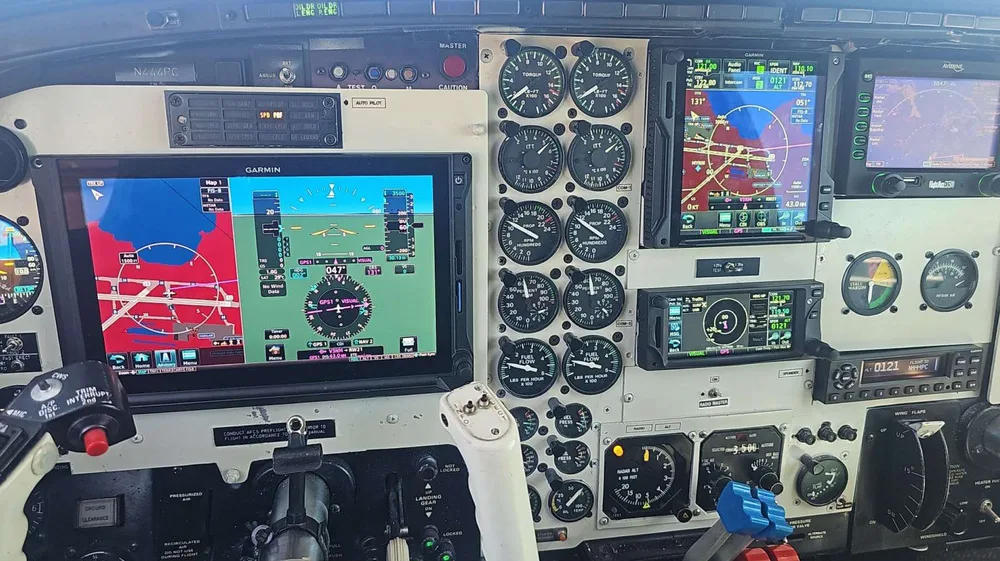 A close-up view of the Piper PA-31 Navajo cockpit, highlighting the Garmin digital displays and various flight instruments.