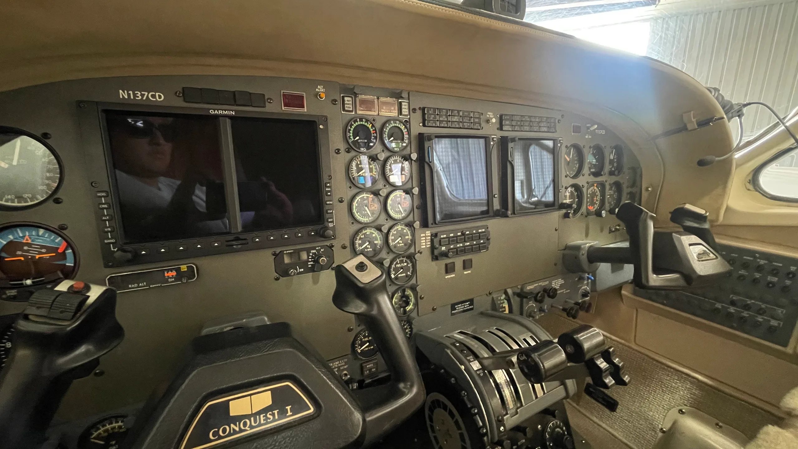 Close-up of the aircraft's instrument panel showing Garmin displays, analog gauges, and "Conquest I" on the yoke.