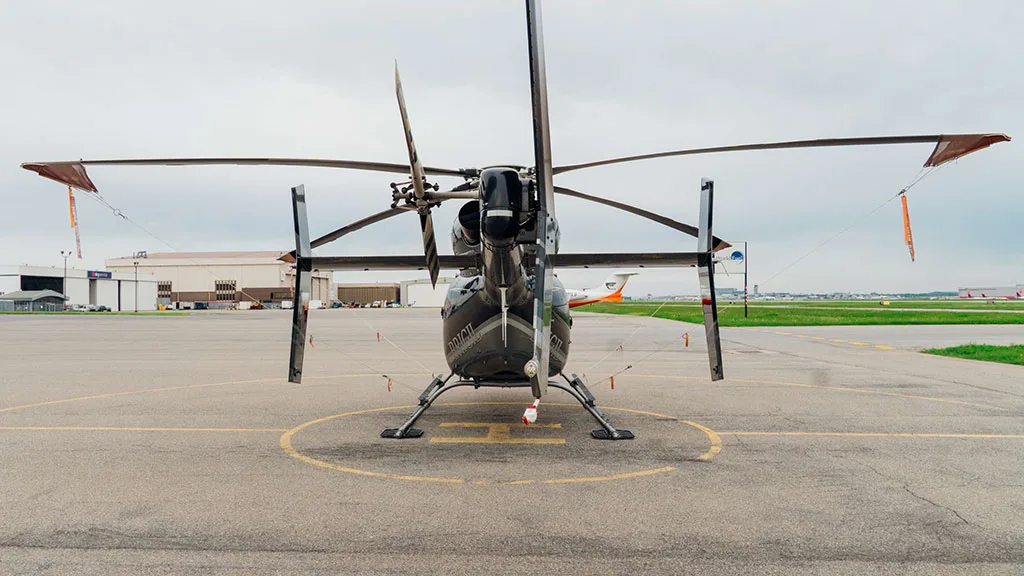 A rear view of the black and silver Bell 427 helicopter parked on an airfield.