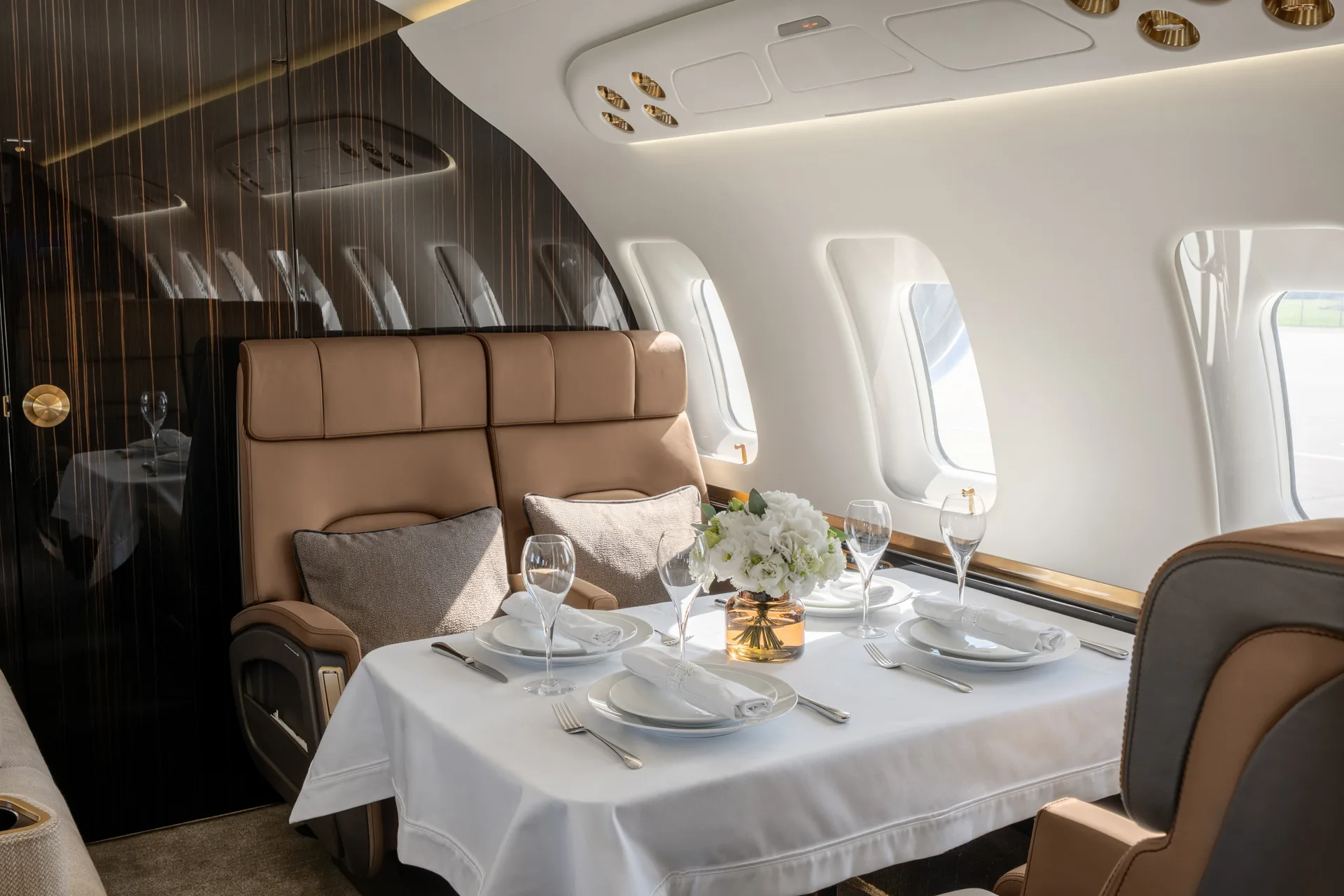 A close-up view of the aircraft's dining area with a white tablecloth, place settings, and a floral centerpiece.
