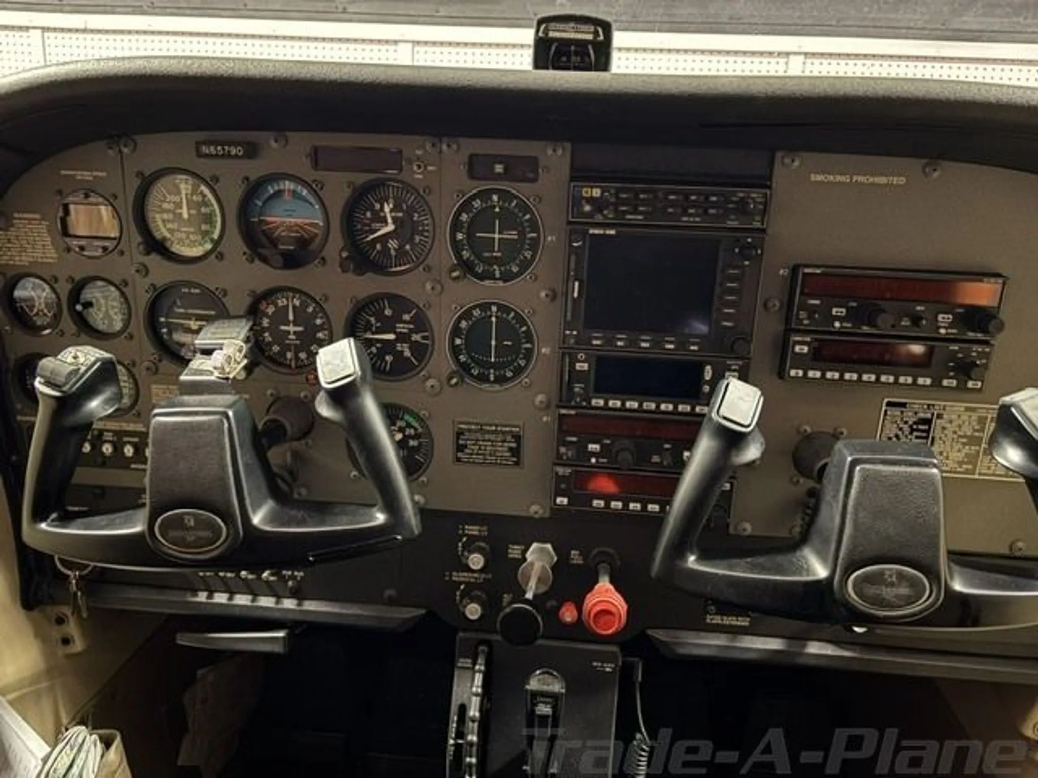 The full instrument panel and dual yokes of a Cessna N65790 cockpit.