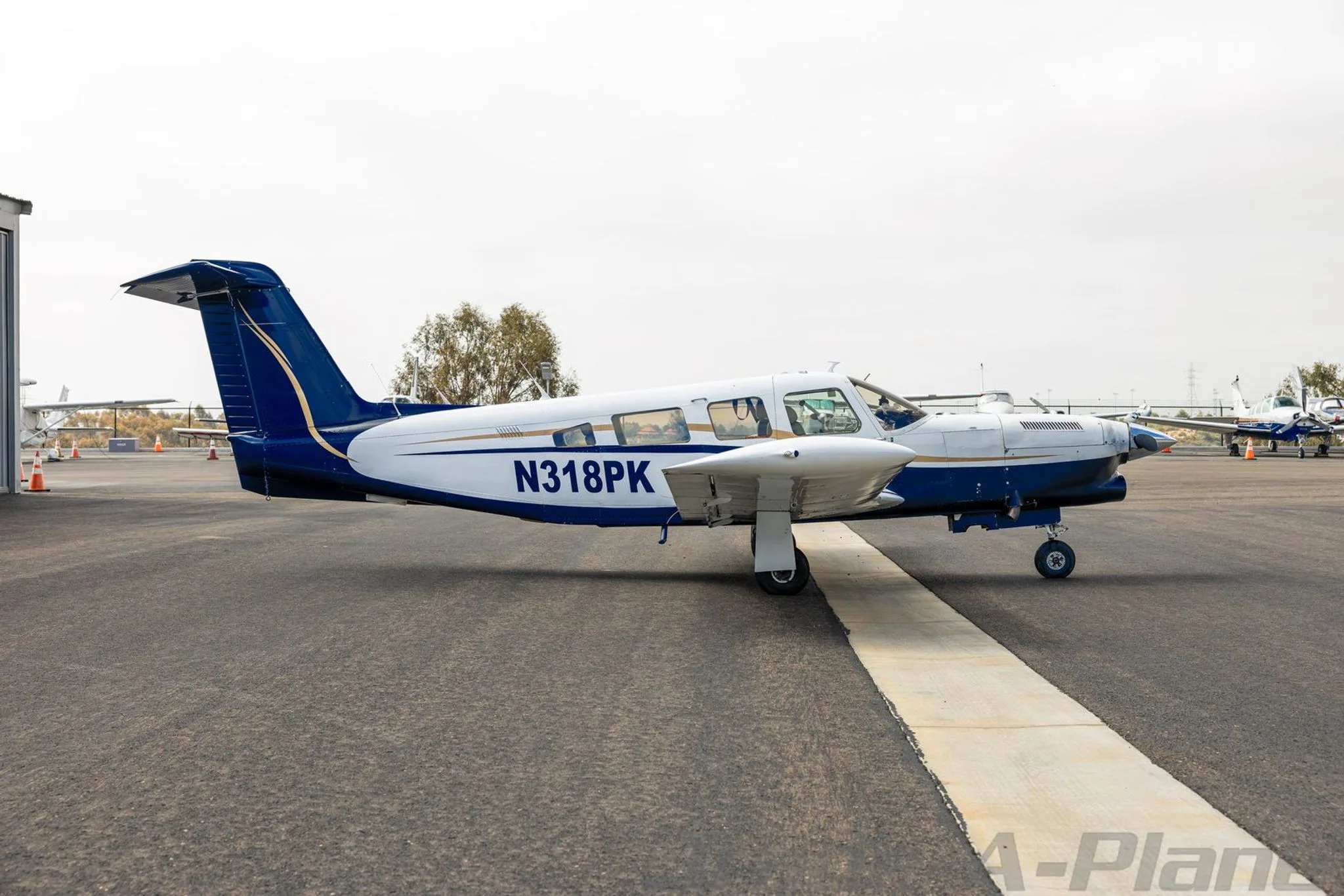 A side profile view of the white and blue Piper aircraft N318PK parked on an airport tarmac.