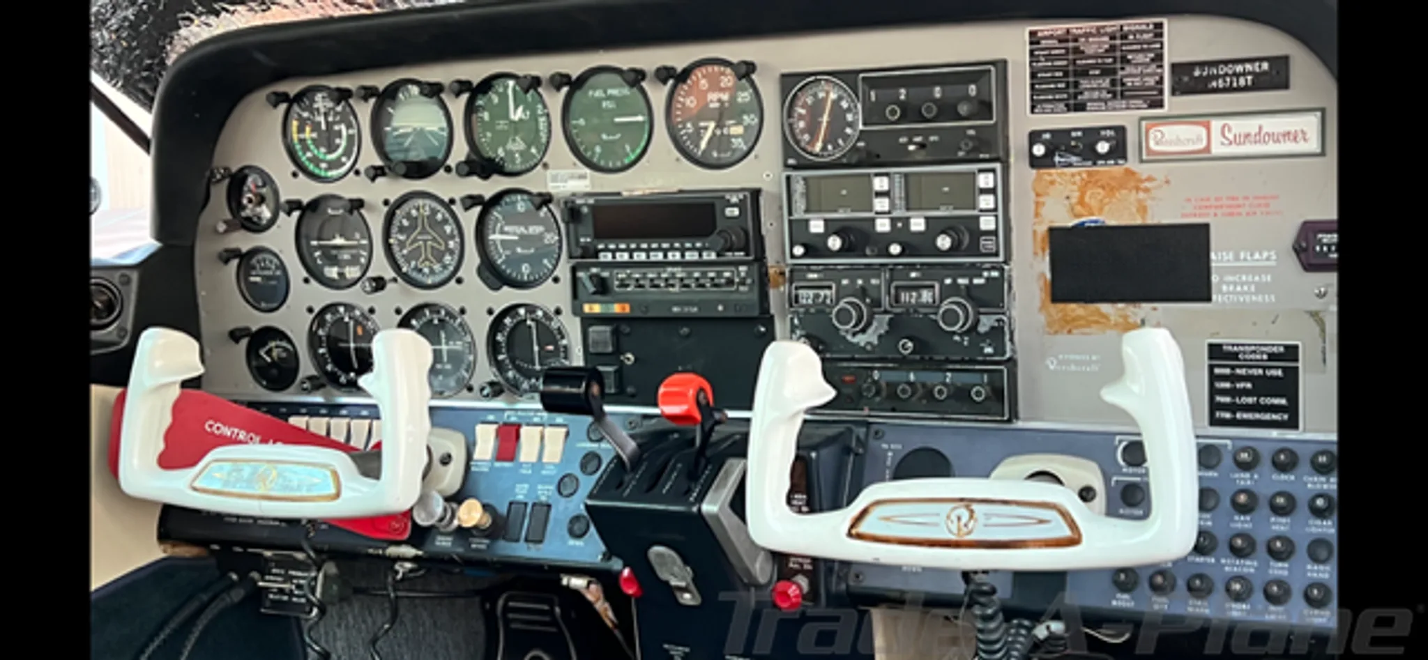 The cockpit of a Beechcraft Sundowner, showing the instrument panel with gauges and two control yokes.