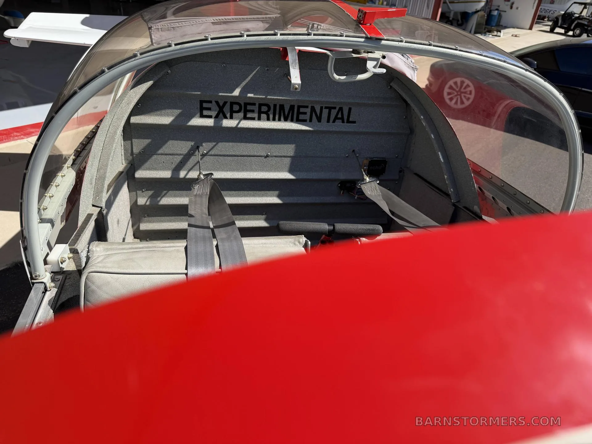 The interior of the Vans RV-7A aircraft, showing the rear baggage area with "EXPERIMENTAL" written on the bulkhead and seatbelts.