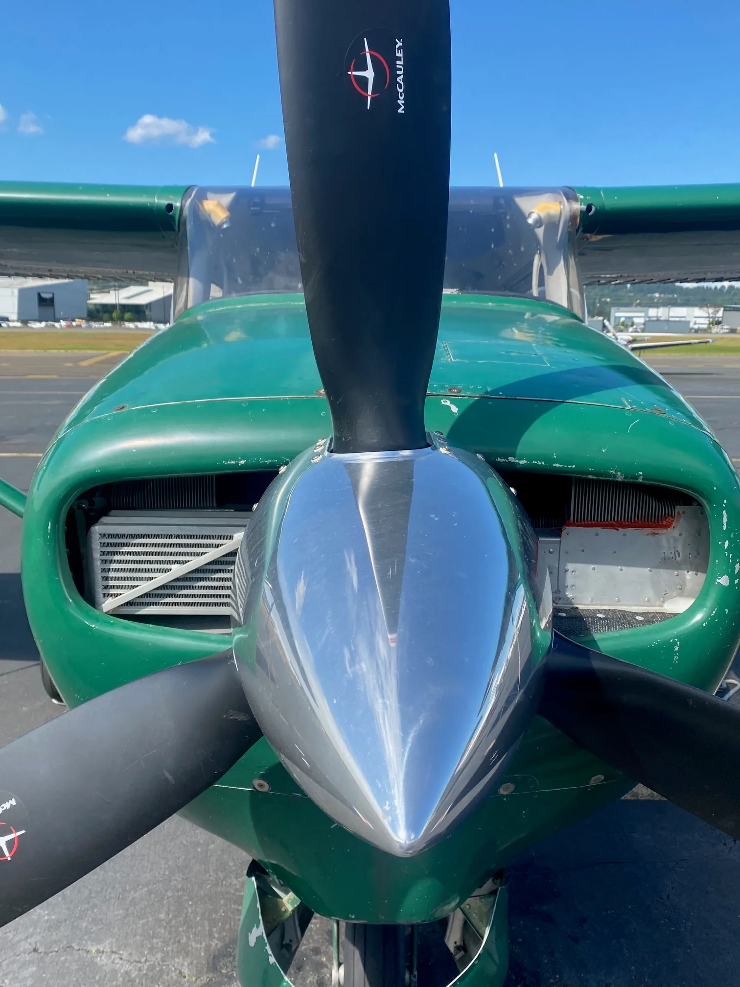 Front view of a green Cessna 210 aircraft showing the propeller and engine cowling.