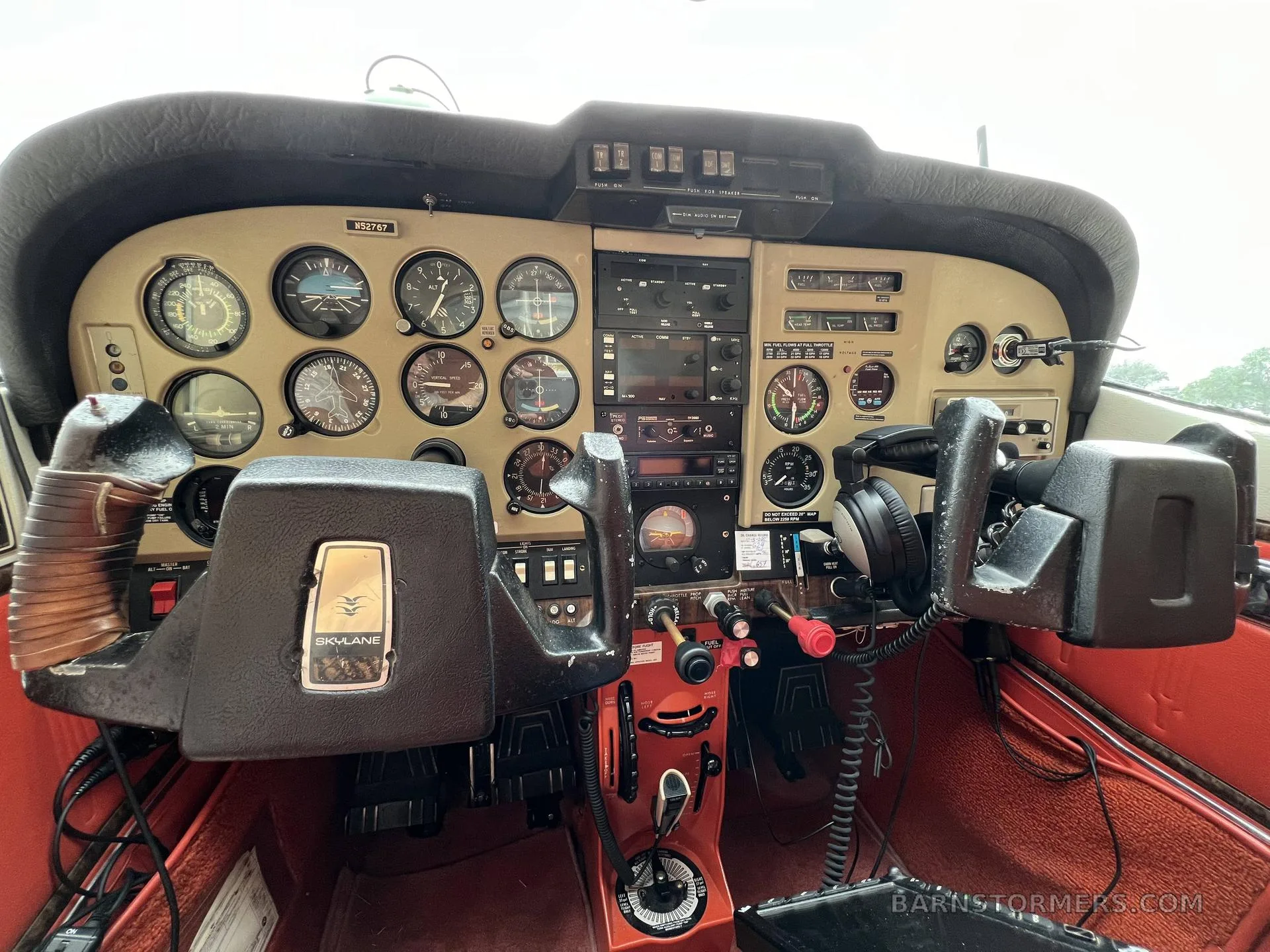 The cockpit of a Cessna Skylane aircraft, showing the instrument panel, yokes, and avionics.