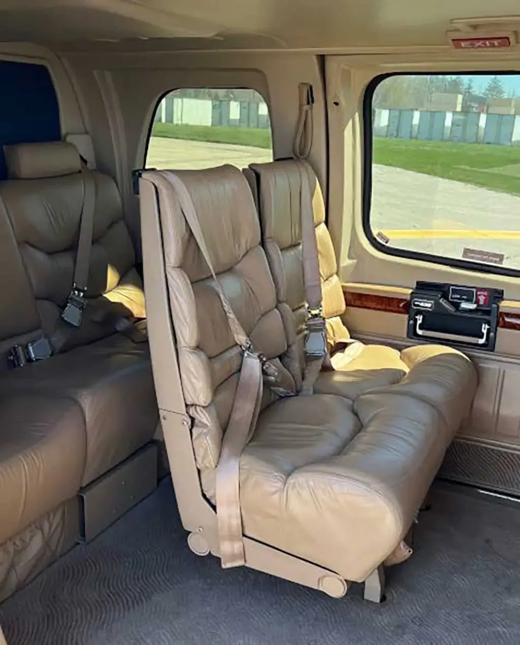 The tan leather interior cabin of a helicopter features plush seats and large windows.