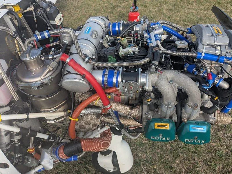 A detailed view of the Rotax aircraft engine, showing complex plumbing and components.